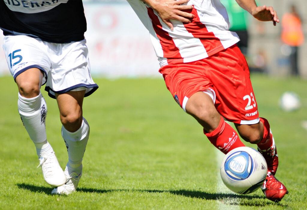 Dos jugadores de fútbol disputan el balón cerca de la línea lateral.