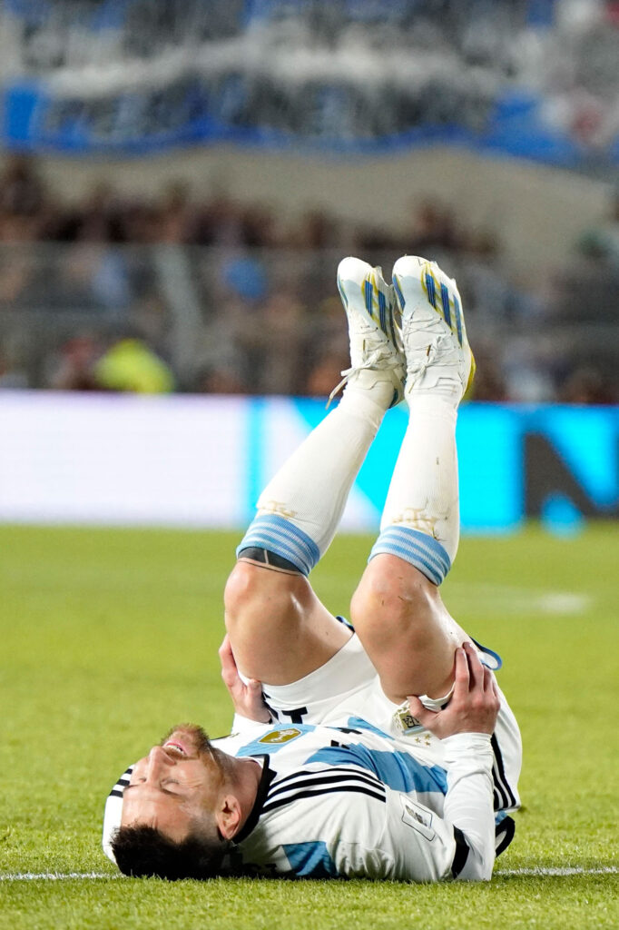 Messi se encuentra acostado en el piso, con las piernas para arriba durante un partido de la Selección Argentina de fútbol.