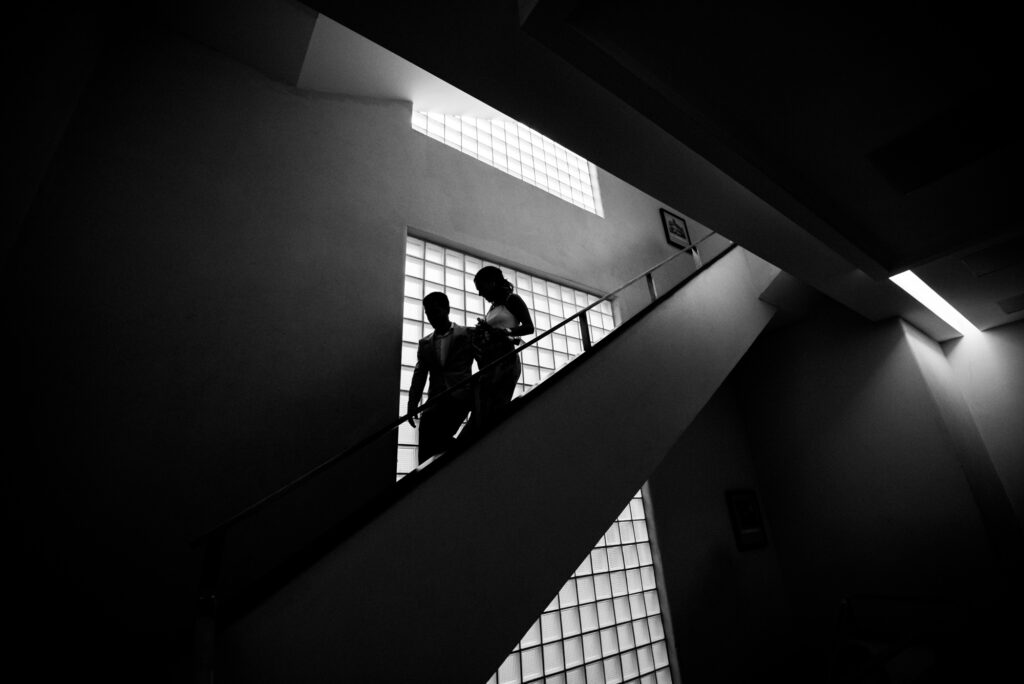 Una pareja baja por las escaleras del registro civil, generando siluetas al pasar por una ventana.