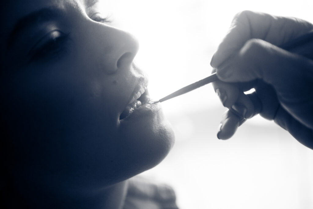 Retrato de una mujer mientras le maquillan los labios.