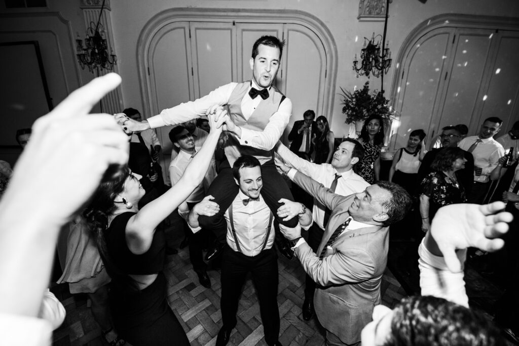 El novio, subido a los hombros de un amigo, bailando en su casamiento.