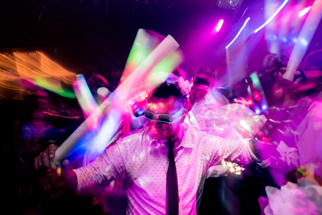 Un hombre baila en el centro de la imagen, con bastones de luces de todos los colores.