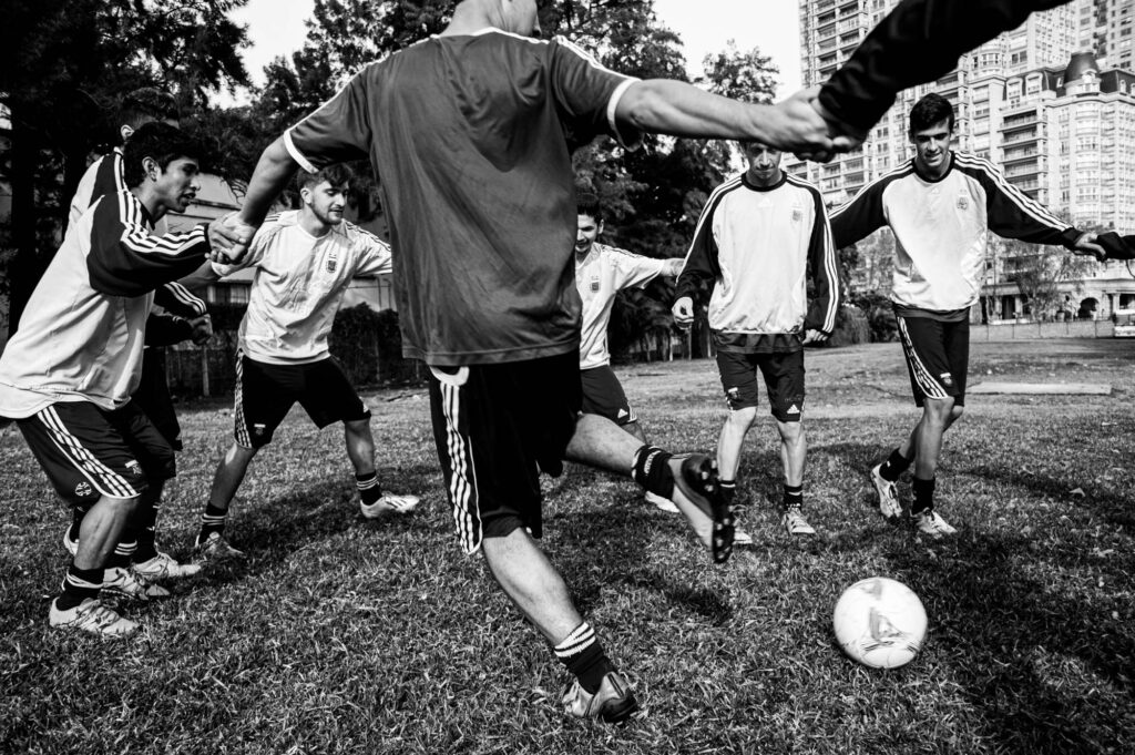 Jugadores de futbol realizando pases formando un círculo tomados de de las manos durante la entrada en calor.