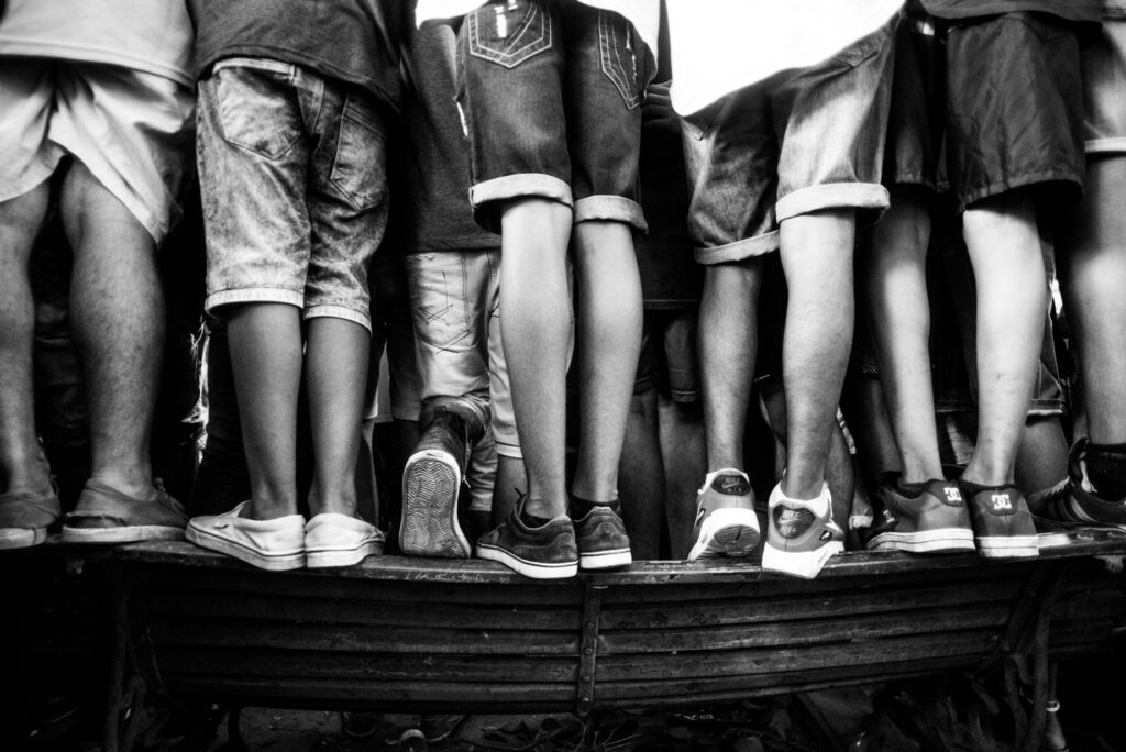 Las piernas de un grupo de jóvenes subidos a un banco de plaza para tratar de ver las batallas de rap en el Parque Rivadavia.